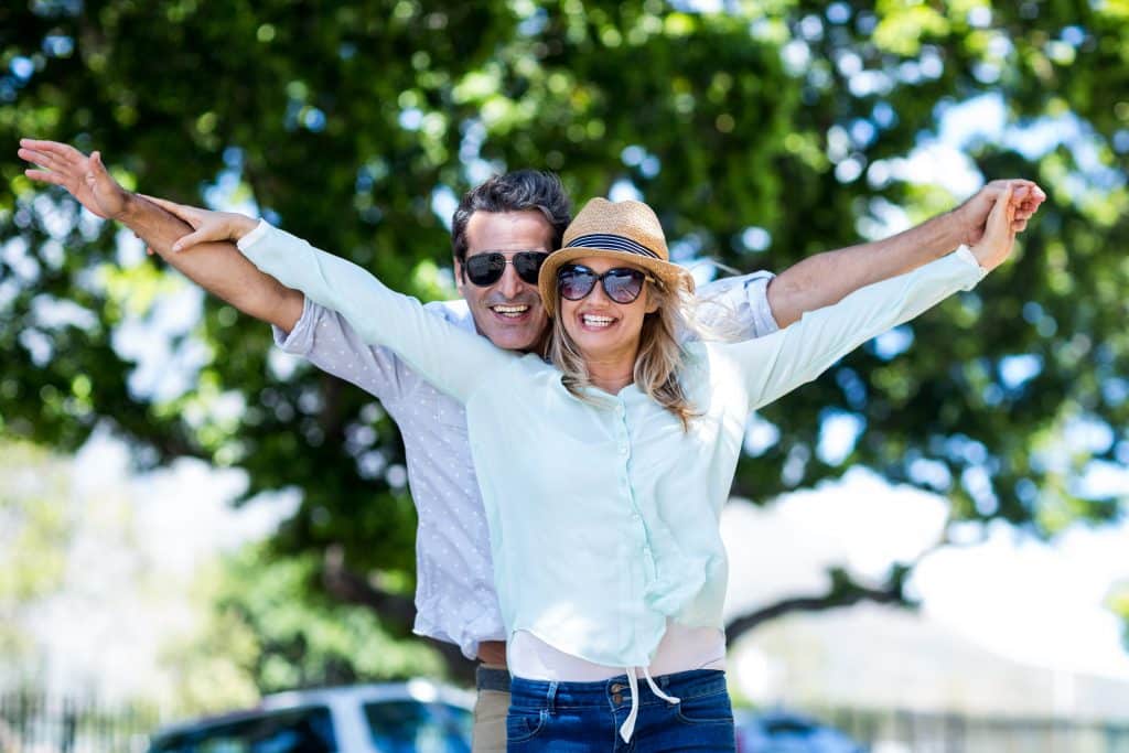 Couple with arms outstretched standing on street